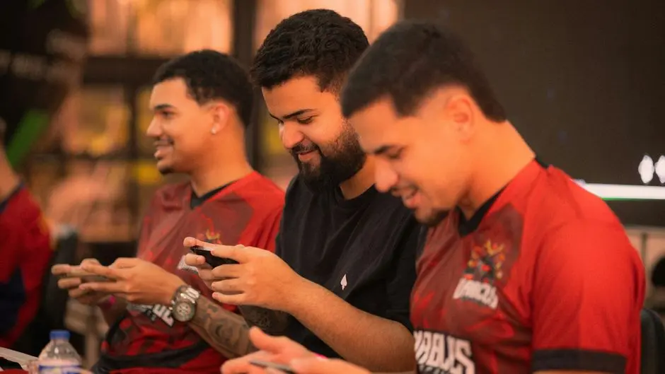 alt dua pemain muda sedang bermain game bersama di depan layar smartphone